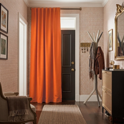 Burnt Orange Thermal Door Curtain in a Hallway with Red Floral Wallpaper and a Rattan Storage Cabinet