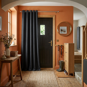 Charcoal Grey Thermal Door Curtain in a Hallway with Terracotta Walls and Natural Oak Furniture