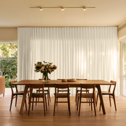Cream Linen S-Fold Dining Room Curtain in a Modern Dining Room with Beige Walls and a Long Wooden Table Featuring a Floral Centerpiece.