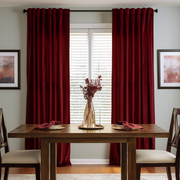 Elegant dining room with deep red curtains, wooden furniture, and warm accents