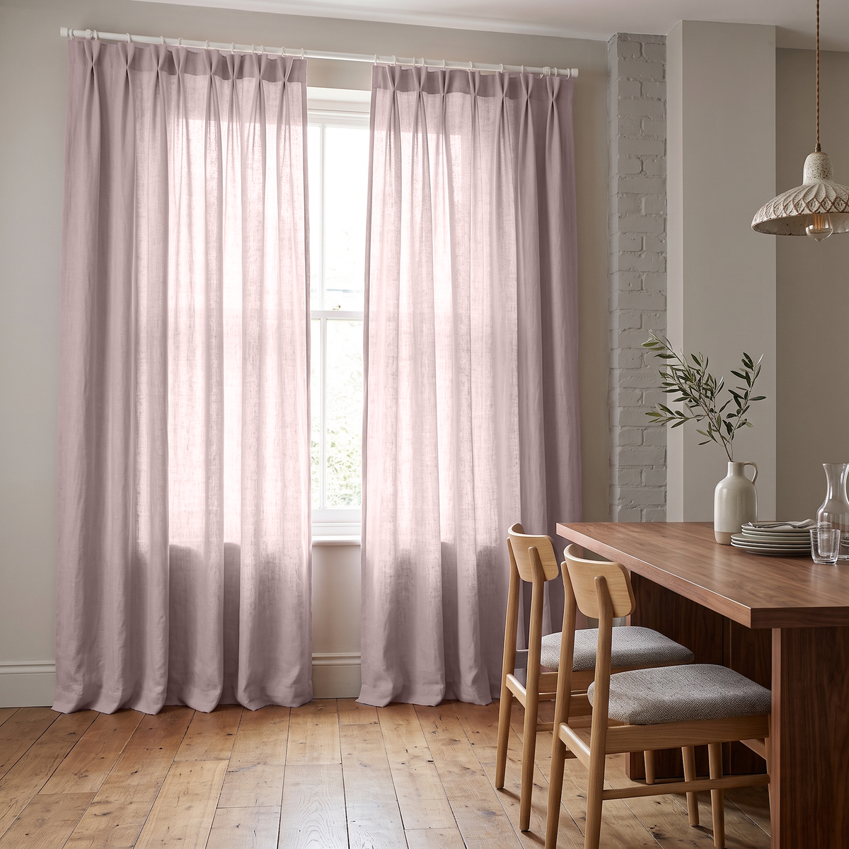 Dusty Pink Linen Pinch Pleat Dining Room Curtain in a Rustic Dining Room with Light Grey Walls and Wide Plank Wood Flooring Beneath a Wooden Dining Table.