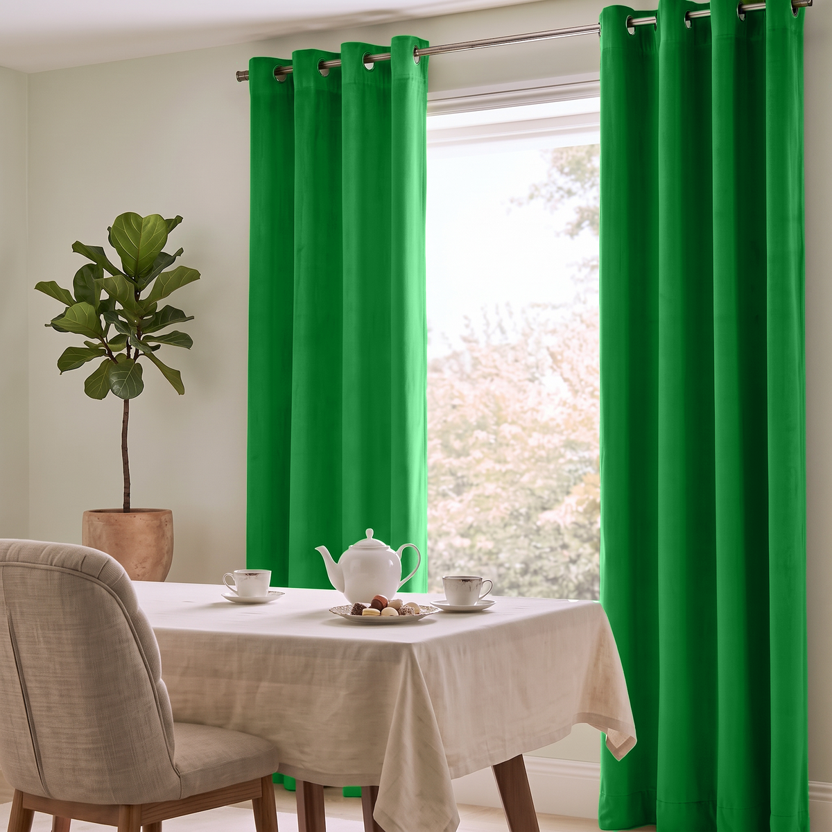 Bright green grommet curtains hanging on a window in a dining room setting, with a table covered in a cream cloth, a white teapot and cups, and a potted plant nearby.