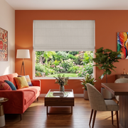Natural Roman Blinds in a Contemporary Living Room with Terracotta Walls and a Coral Sofa