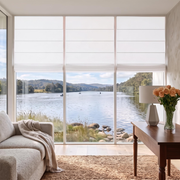 Off-White Roman Blinds in a Living Room with Light Neutral Walls and a Beige Armchair