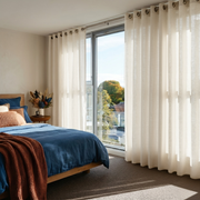 Cream Linen Eyelet Curtains in a Bright Bedroom With Blue Bedding and Large Sunlit Windows