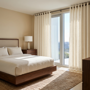 Cream Linen Eyelet Curtains in a Warm Neutral Bedroom With a Wooden Bed and Floor-to-Ceiling Windows