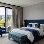 Natural Linen Pencil Pleat Curtains in a Modern Bedroom with Deep Blue Accents 