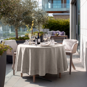 Natural Linen Round Tablecloth in a Sunlit Outdoor Dining Setting with Olive Trees