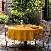 Mustard Yellow Linen Round Tablecloth in a Garden Patio Dining Space with Natural Woven Brown Chairs