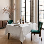 Off-White Rectangular Linen Tablecloth in a Contemporary Loft Dining Room with Floor-to-Ceiling Windows and Green Velvet Chairs
