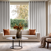 Off-White Velvet Eyelets Extra Long Curtains in a Bright, Modern Living Room with Beige Sofa, Orange-Brown Pillows, and a Round Coffee Table