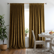 Dining room with floor-length gold curtains, a white table, and a potted plant.
