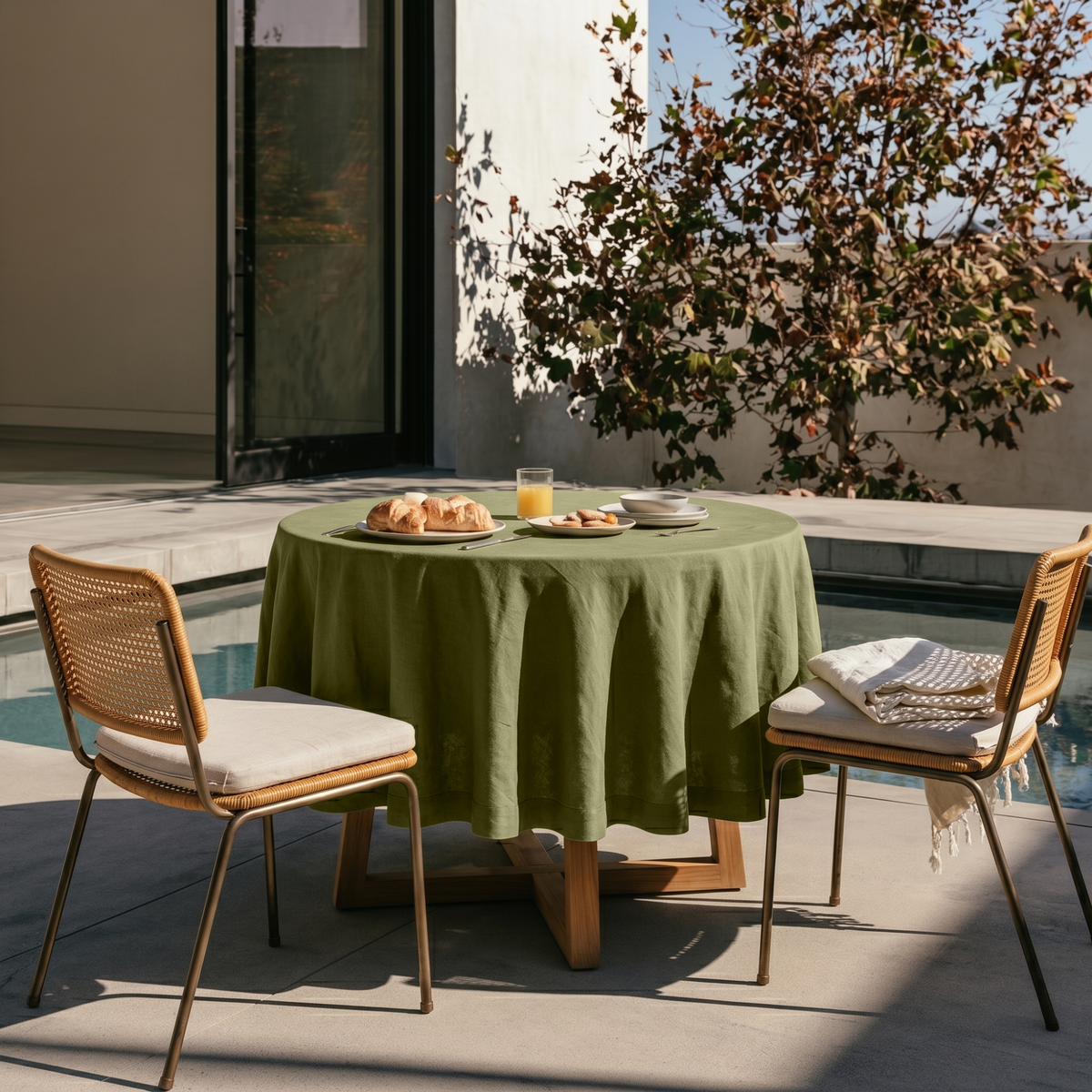 Olive Green Linen Round Tablecloth in a Sunlit Patio Dining Space with Smooth Concrete Walls and Honey Rattan and Warm Wood Accents
