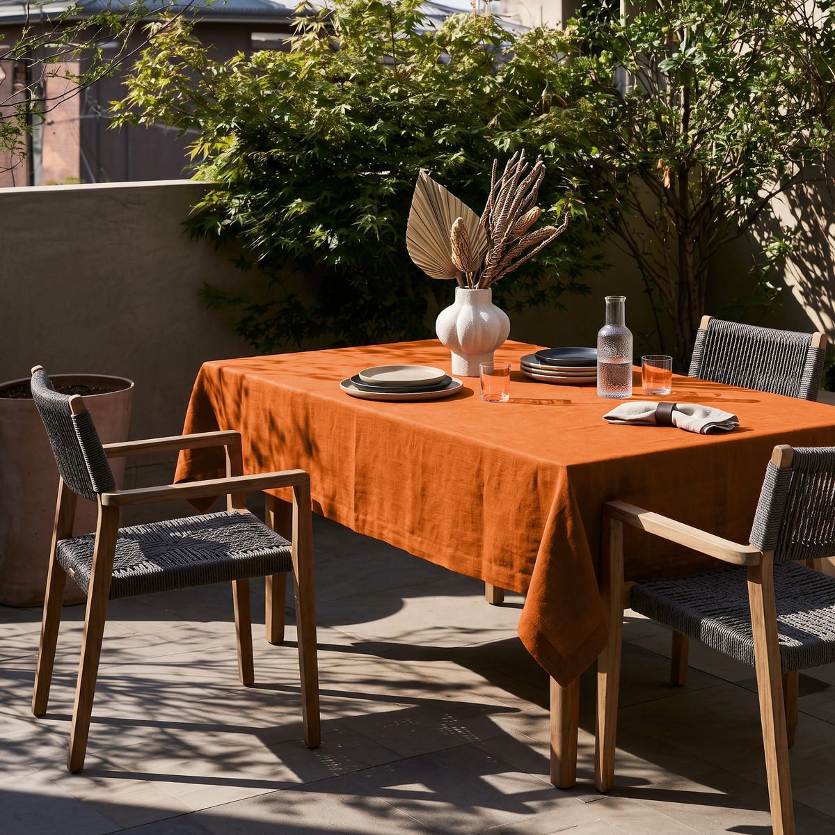 Burnt Orange Rectangular Linen Tablecloth in a Contemporary Outdoor Dining Area with Woven Chairs