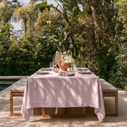 Dusty Pink Rectangular Linen Tablecloth in a Tropical Outdoor Dining Area with Wooden Bench Seating