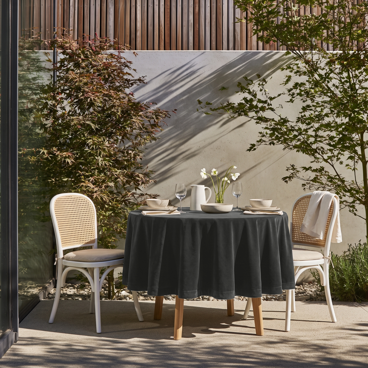 Dark Grey Round Velvet Tablecloth on a Garden Patio with White Cane Chairs