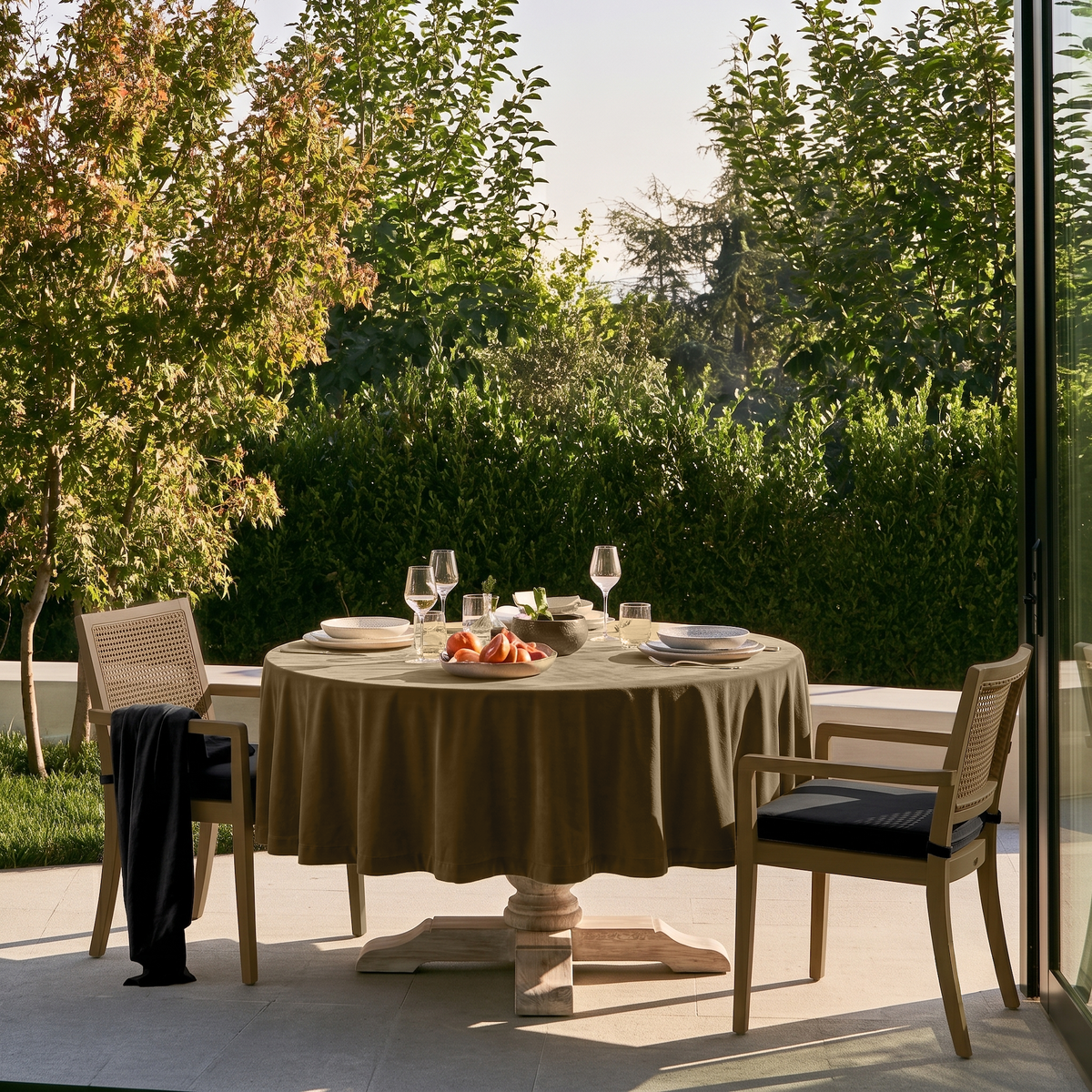 Olive Brown Round Velvet Tablecloth in an Outdoor Dining Area with Garden Views and Light Patio Chairs
