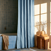 Sky Blue Linen Button-Hole Top Weighted Shower Curtain in a Cozy Bathroom with Blue Tiles in Morning Light