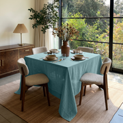 Aquamarine Blue Square Linen Tablecloth in a Bright Contemporary Dining Room with Bouclé Chairs