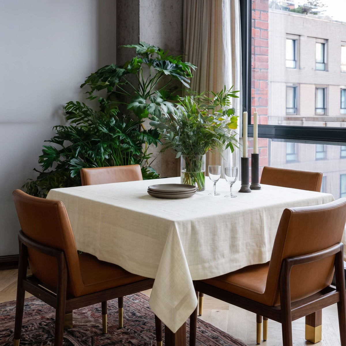 Cream Square Linen Tablecloth in a Contemporary Dining Room with Tan Leather Chairs and Indoor Greenery