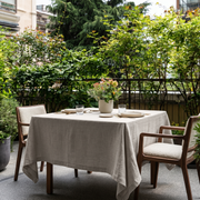 Natural Square Linen Tablecloth on a Contemporary Outdoor Terrace with Lush Greenery and Wooden Armchairs