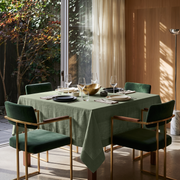 Asparagus Green Square Linen Tablecloth in a Contemporary Dining Room with Green Velvet Chairs and Warm Wood Paneling