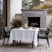 White Square Linen Tablecloth in a Contemporary Outdoor Patio with Stone Fireplace and Grey Armchairs