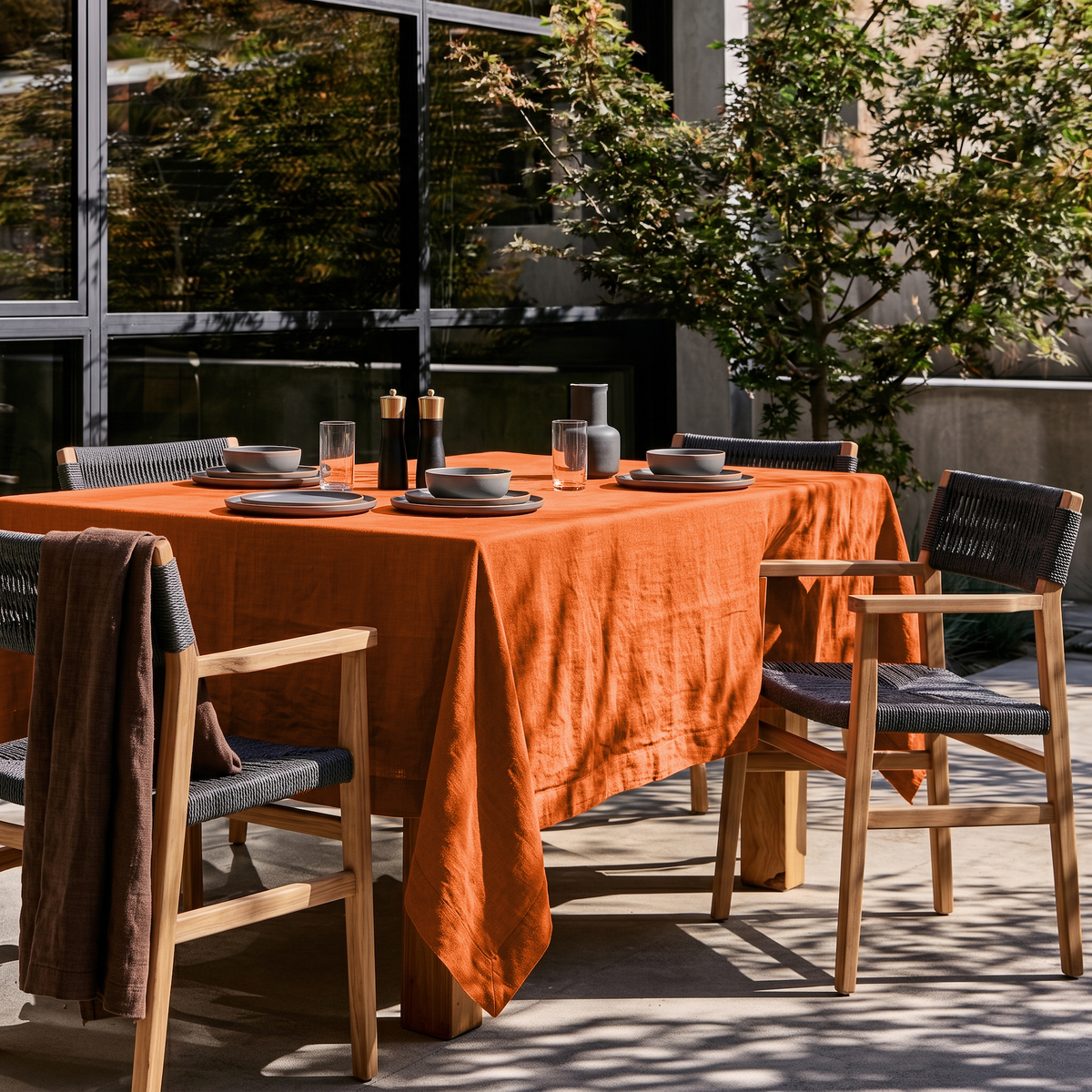 Burnt Orange Square Linen Tablecloth in a Modern Outdoor Dining Area with Wooden Chairs