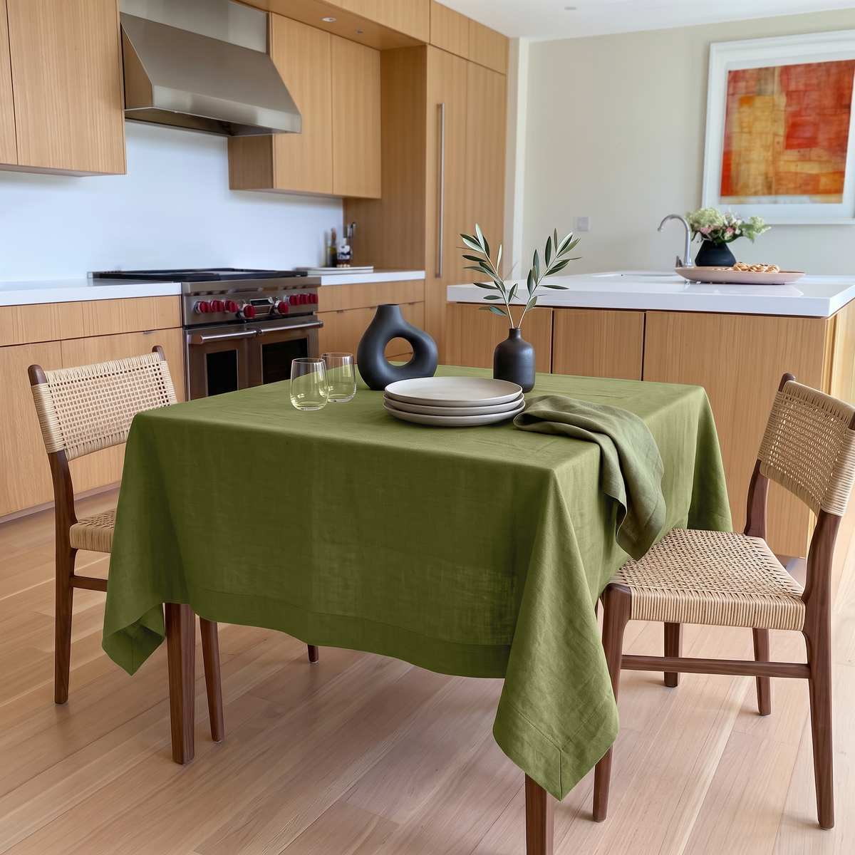 Moss Green Square Linen Tablecloth in a Bright Modern Kitchen with Light Wood Cabinetry and Cane Chairs
