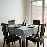Stone Grey Square Linen Tablecloth in a Transitional Dining Room with Dark Wood Chairs and Floor-to-Ceiling Windows