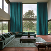 Teal S-Fold Extra Long Curtains in a Contemporary Double-Height Living Room with Teal Sectional Sofa, Green Rug, and Dark Wood Coffee Table