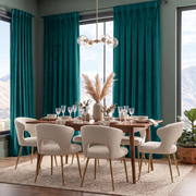 A styled dining room scene with a wooden dining table, six cream upholstered chairs with gold legs, teal curtains, large windows, and a mountain view outside.